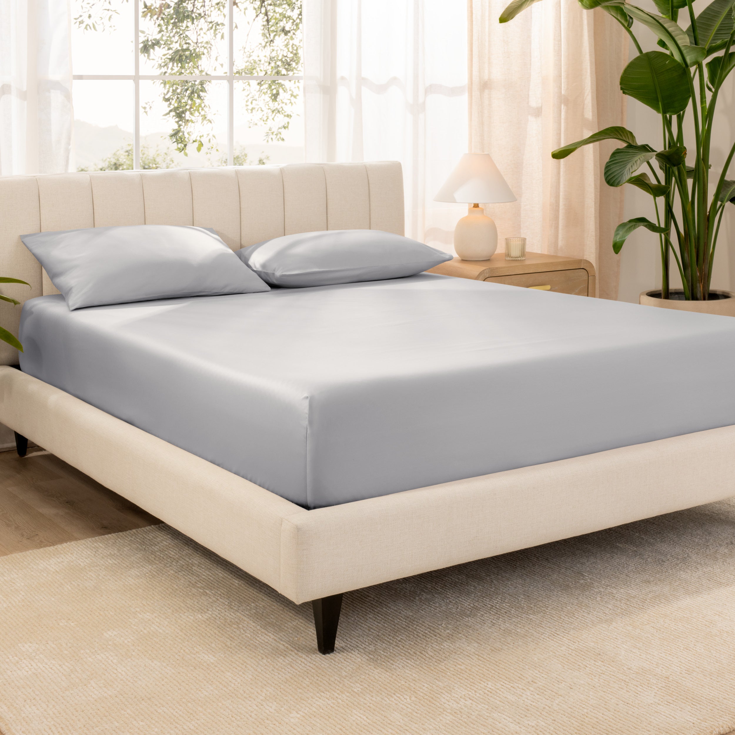 A bed made with an organic cotton sateen fitted sheet and matching pillowcases on pillows