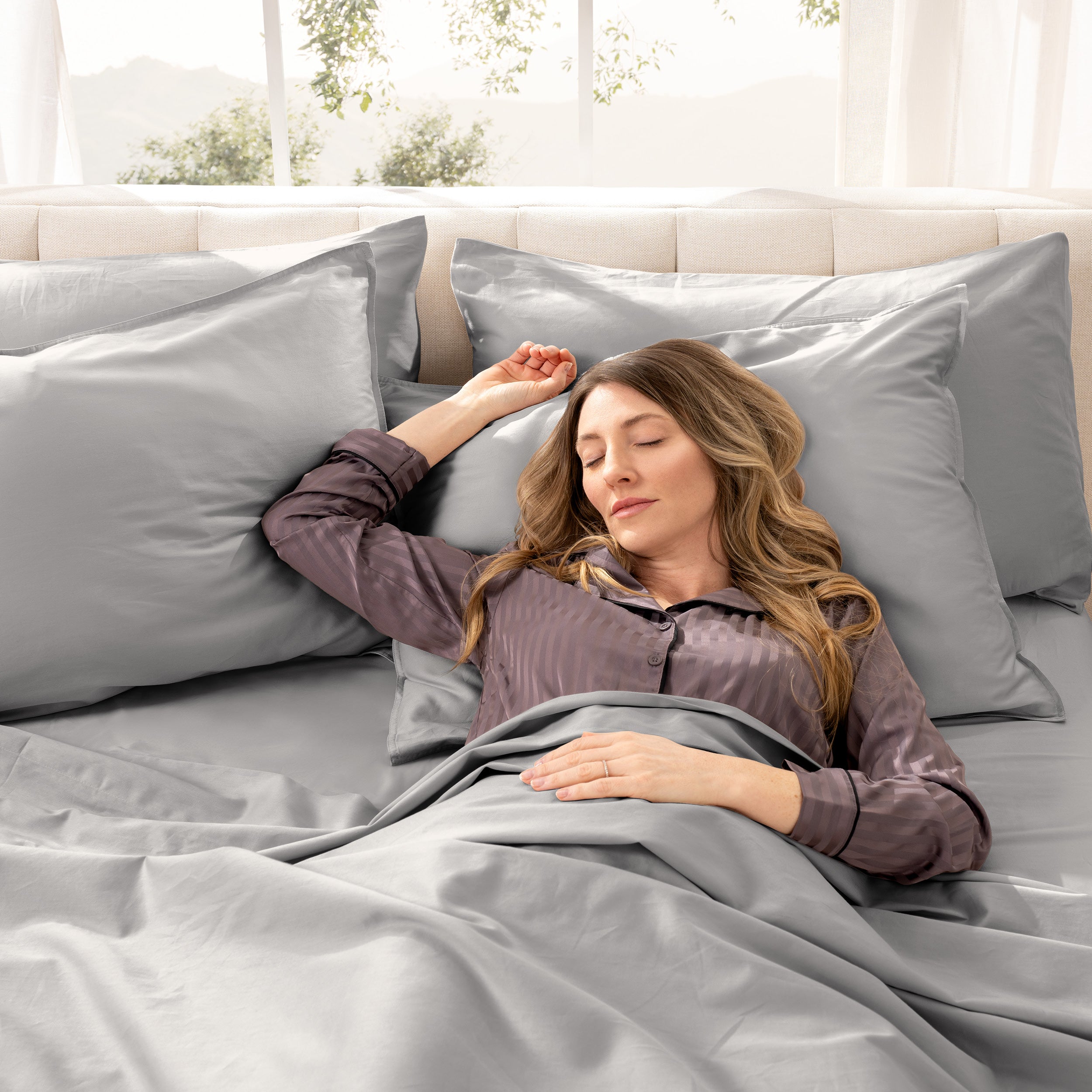 A woman is sleeping on a bed made with organic cotton sateen sheets