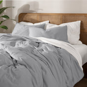 Bedding set on a bed with a wicker nightstand and lamp in a bedroom setting.