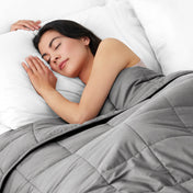 Woman sleeping peacefully under a weighted blanket with white pillows
