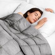 Woman sleeping peacefully under a weighted blanket with white pillows