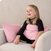 A child sitting while holding a microfiber pillowcase covered pillow