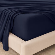 Fitted sheet and top sheet on a mattress with a beige bed frame