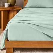 Bed with flannel bedding and wooden headboard and nightstand next to it.