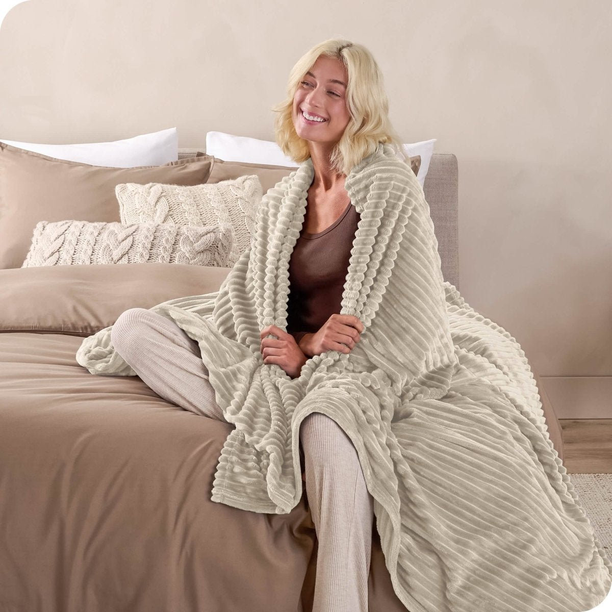 A man sitting on a bed wrapped in a microplush blanket