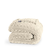 A cable knit sherpa blanket folded neatly