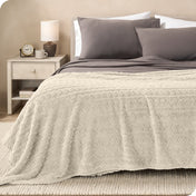 A textured sherpa blanket draped over the end and side of a bed