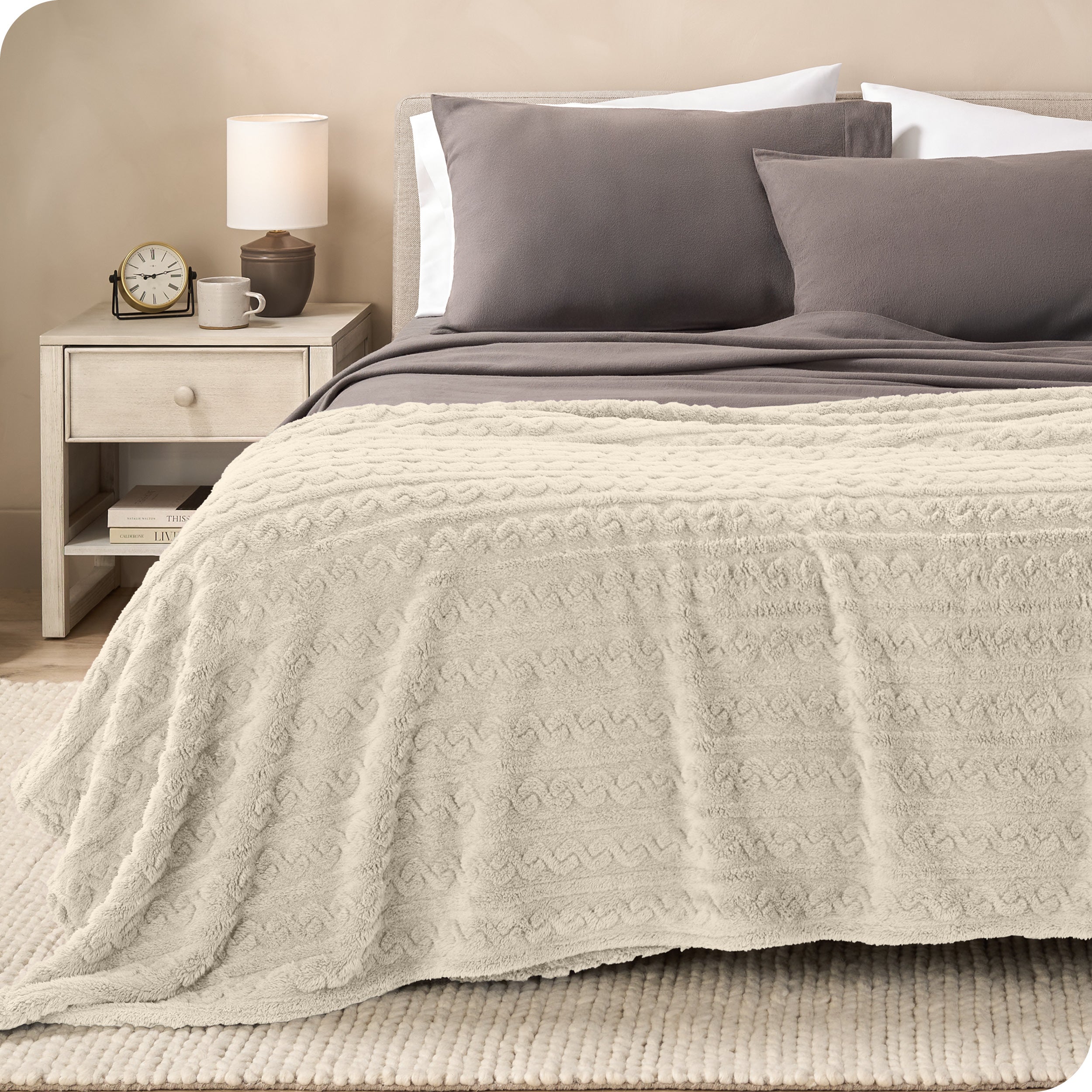 A textured sherpa blanket draped over the end and side of a bed