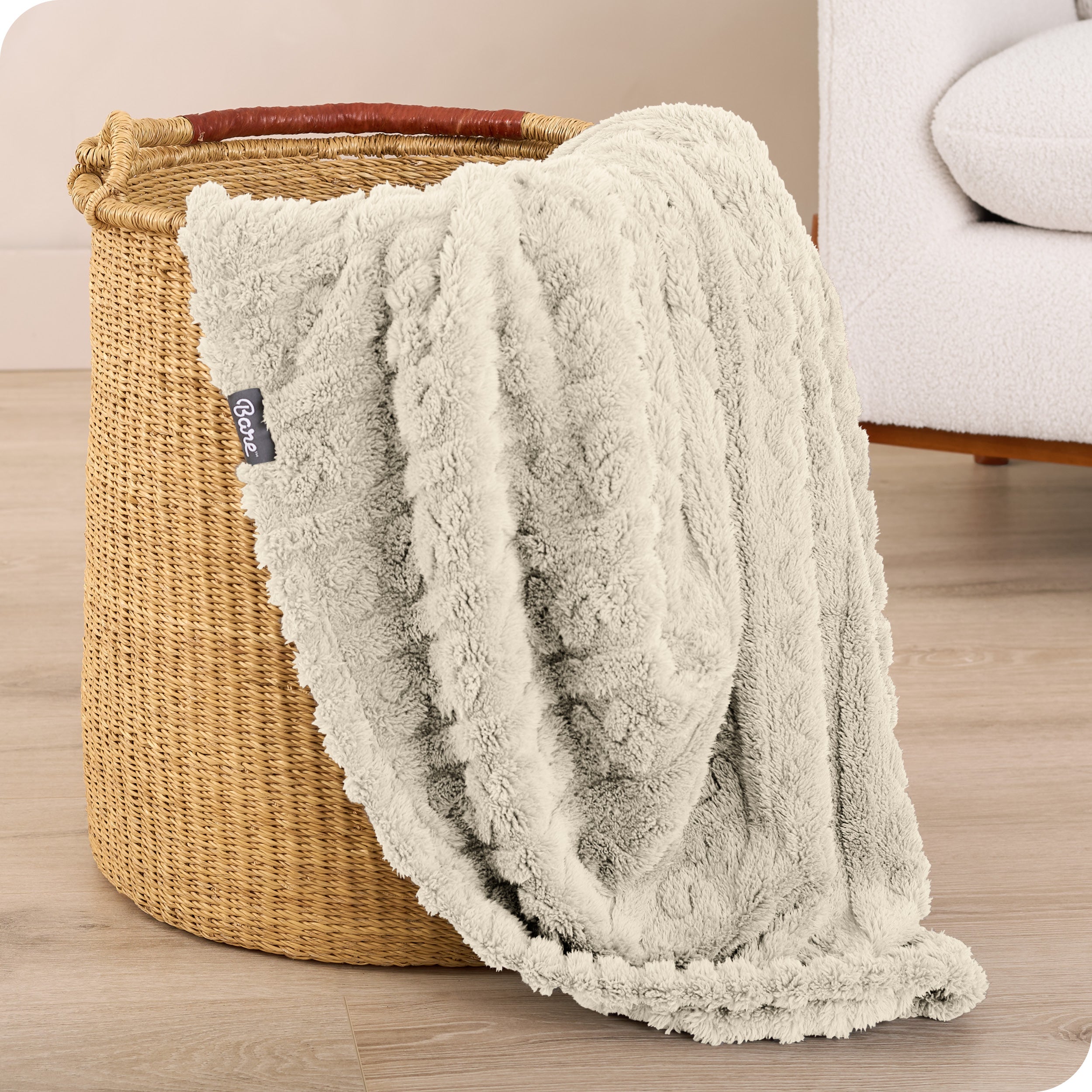 A sherpa blanket is hanging over the edge of a woven hamper
