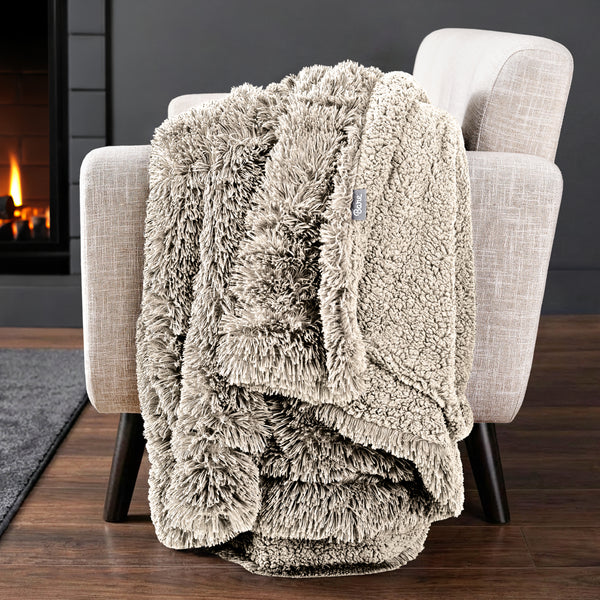 Sherpa blanket draped over an armchair in front of a fireplace.