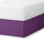 The corner of a bed skirt on a bed frame