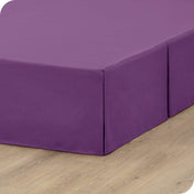 A box spring with a bed skirt on it
