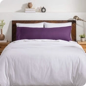 A body pillow cover on a pillow on a bed with other pillows and a duvet cover