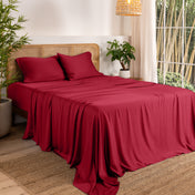Bamboo sheets on a bed in a bedroom with plants and a lamp.