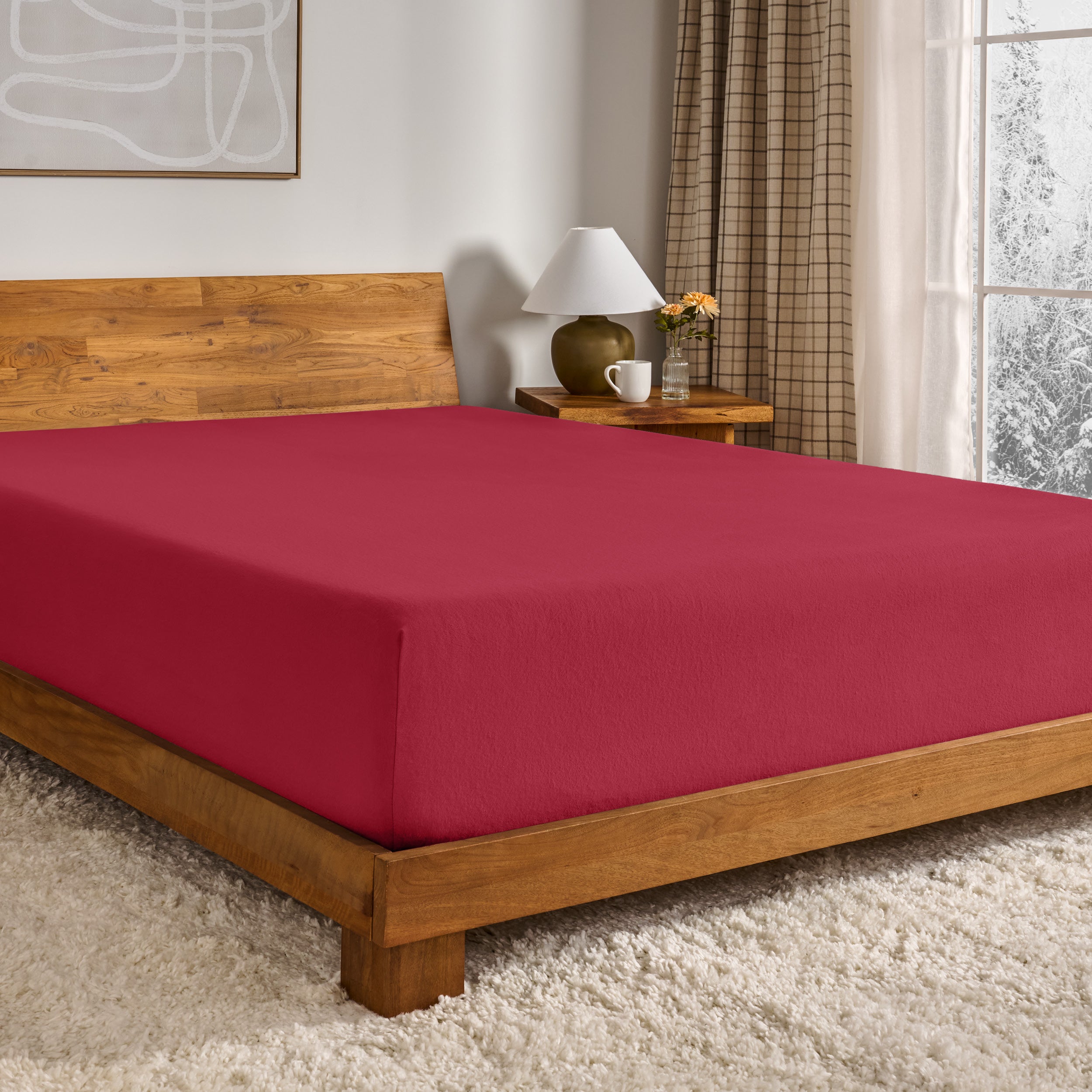 Red fitted sheet on a wooden bed in a bedroom setting