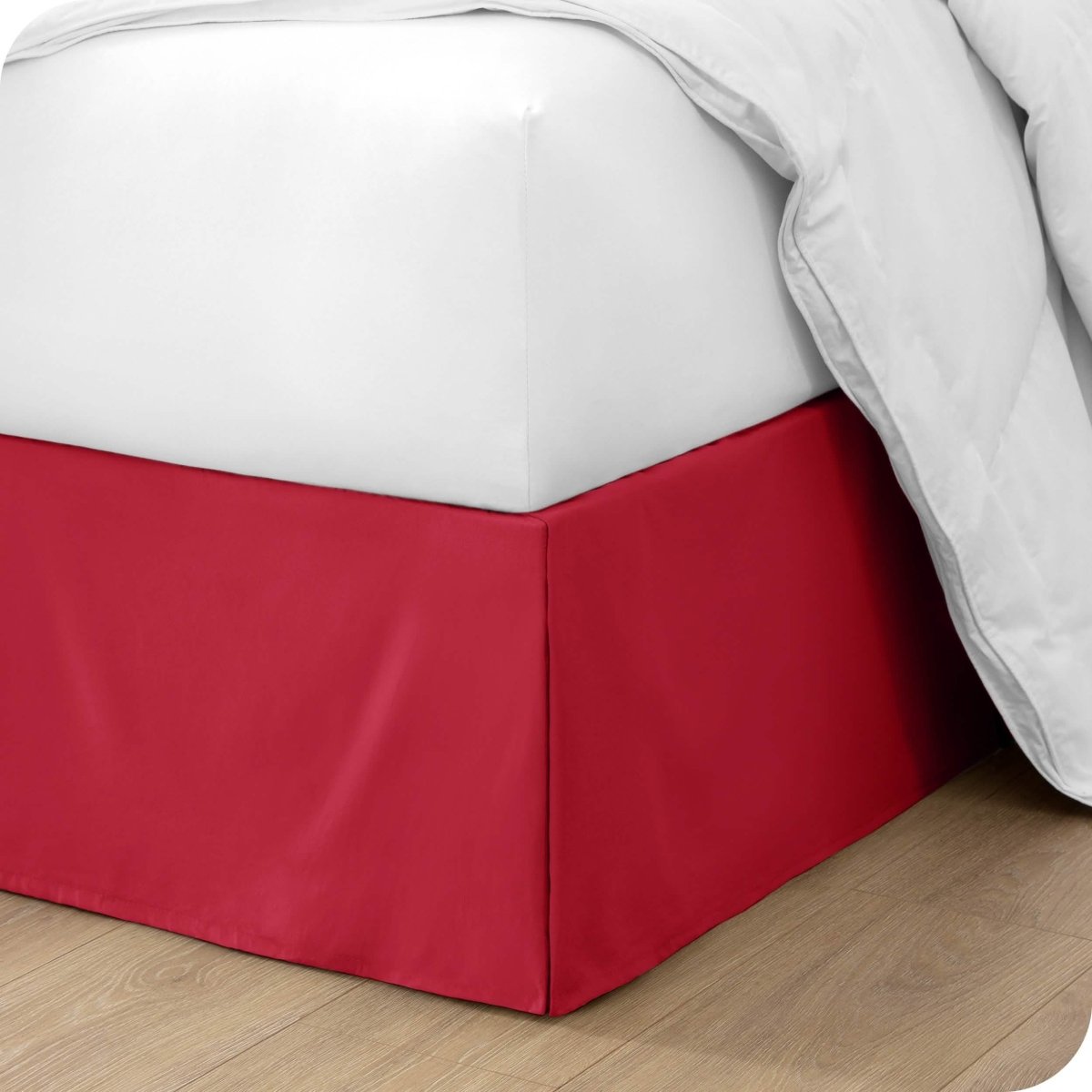 The corner of a bed with a bed skirt and comforter on it