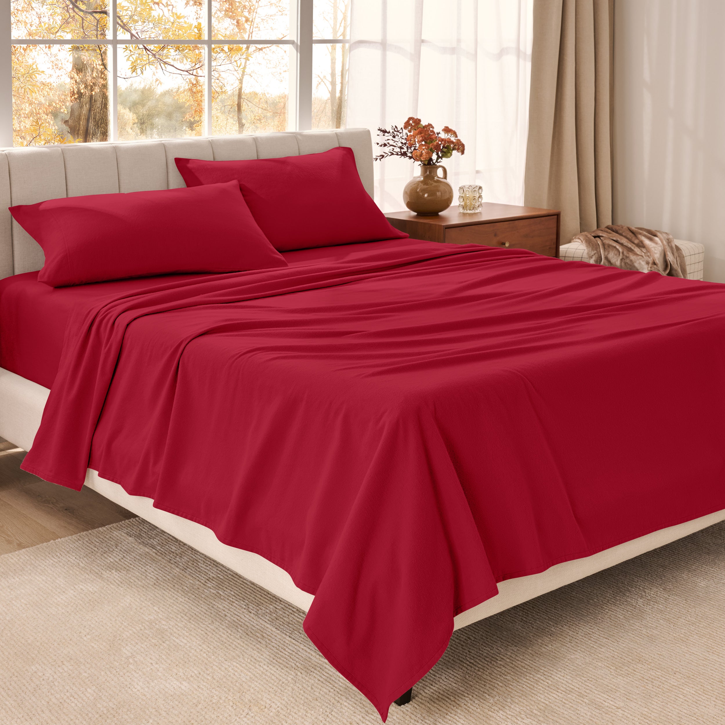 Bed sheets on a neatly made bed in a bright bedroom with large windows.