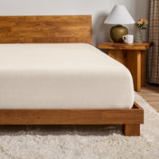 A flannel fitted sheet on a mattress with a wooden bed frame