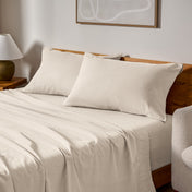 Cotton flannel sheets and pillows on a wooden bed in a bedroom setting.
