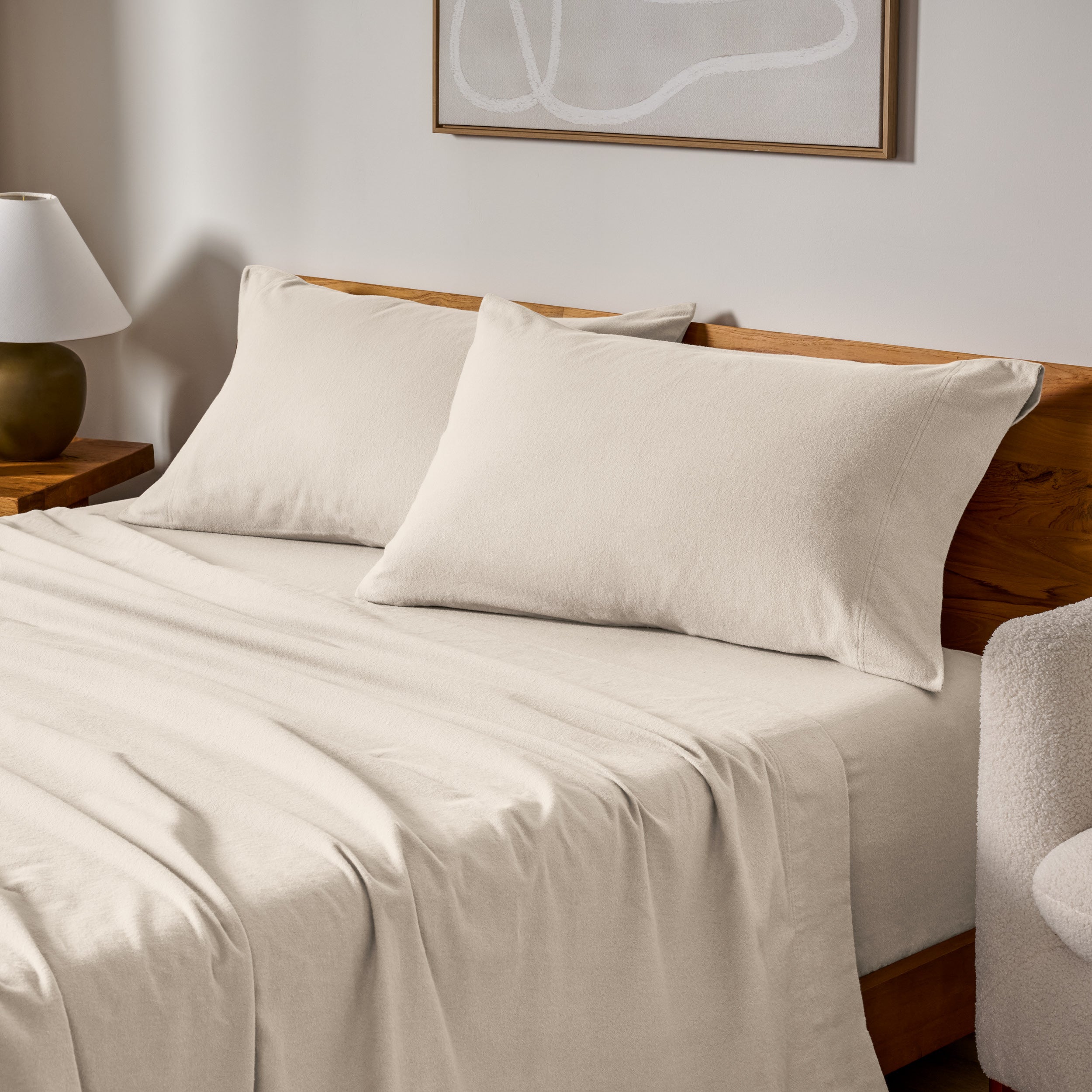 Cotton flannel sheets and pillows on a wooden bed in a bedroom setting.