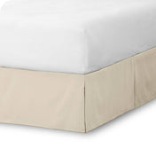 The corner of a bed skirt on a bed frame
