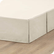 A box spring with a bed skirt on it
