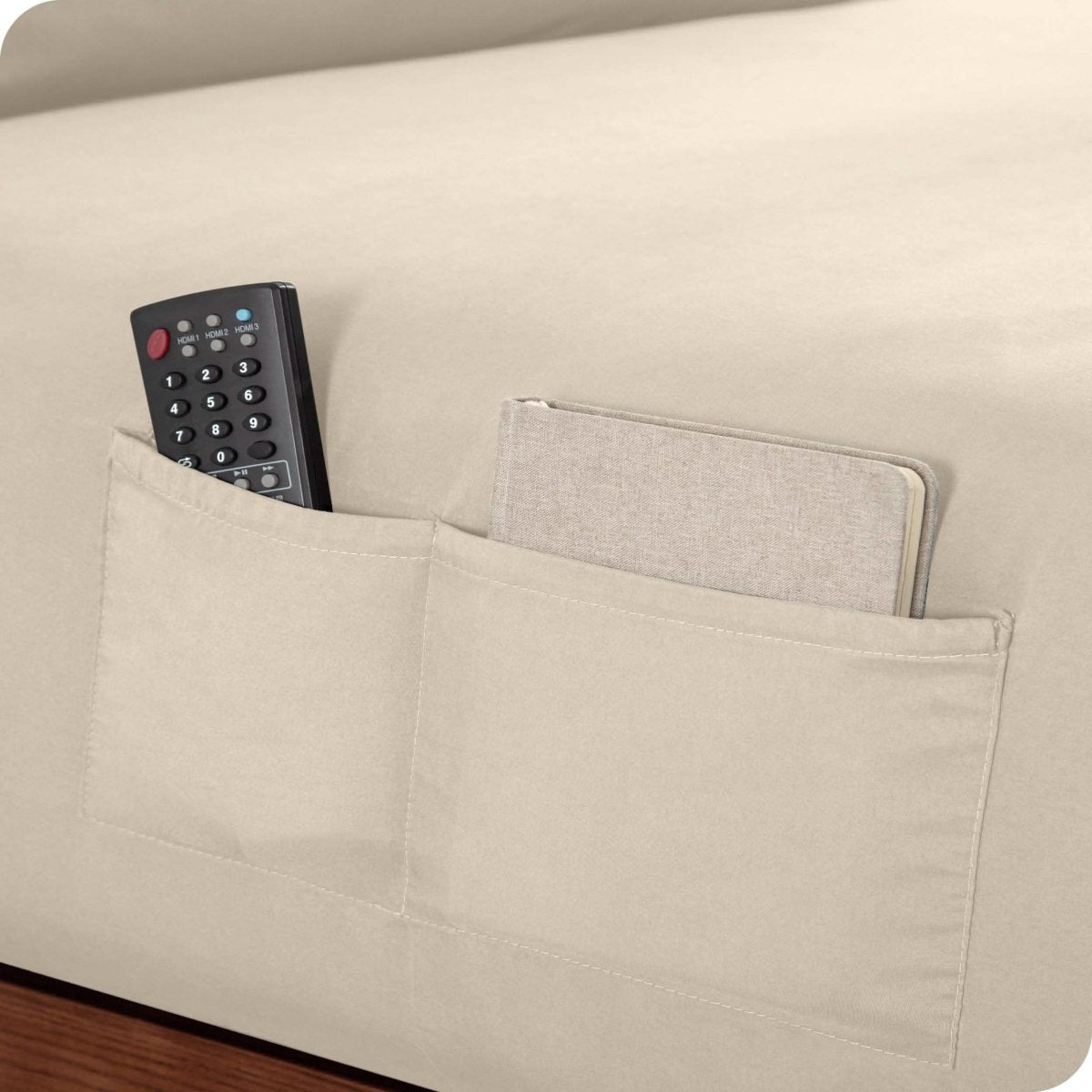 Close up of 2 pockets on a fitted sheet with a remote and journal in the pockets