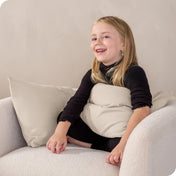 A child sitting while holding a microfiber pillowcase covered pillow