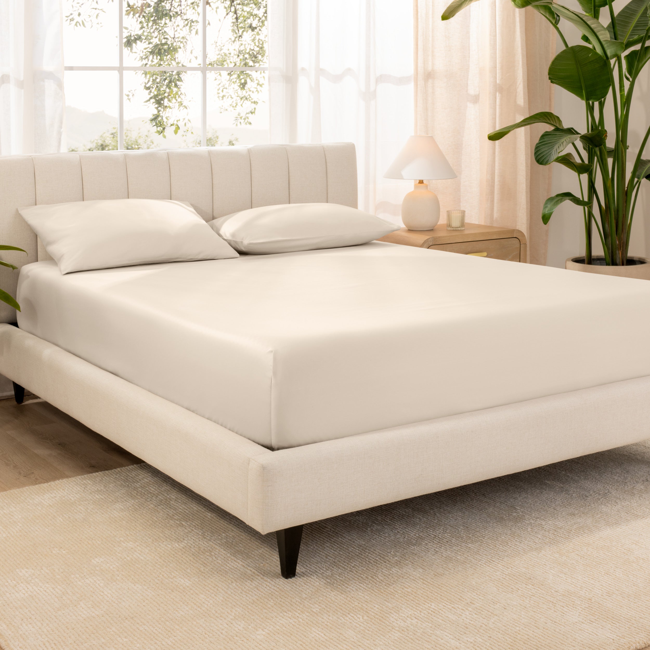 A bed made with an organic cotton sateen fitted sheet and matching pillowcases on pillows