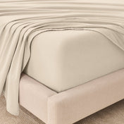 Fitted sheet and top sheet on a mattress with a beige bed frame