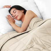 Woman sleeping peacefully under a weighted blanket with white pillows