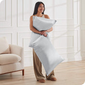 A woman standing while holding pillows with silk pillowcases on them