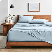 Modern bedroom with washed sheets draped over the end and the side of the bed