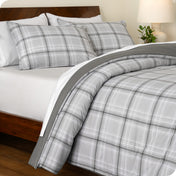 A side view of a printed comforter on a bed with a wooden frame and headboard