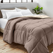 Close up of a comforter on a bed folded over itself. There are also 4 pillows on the bed.
