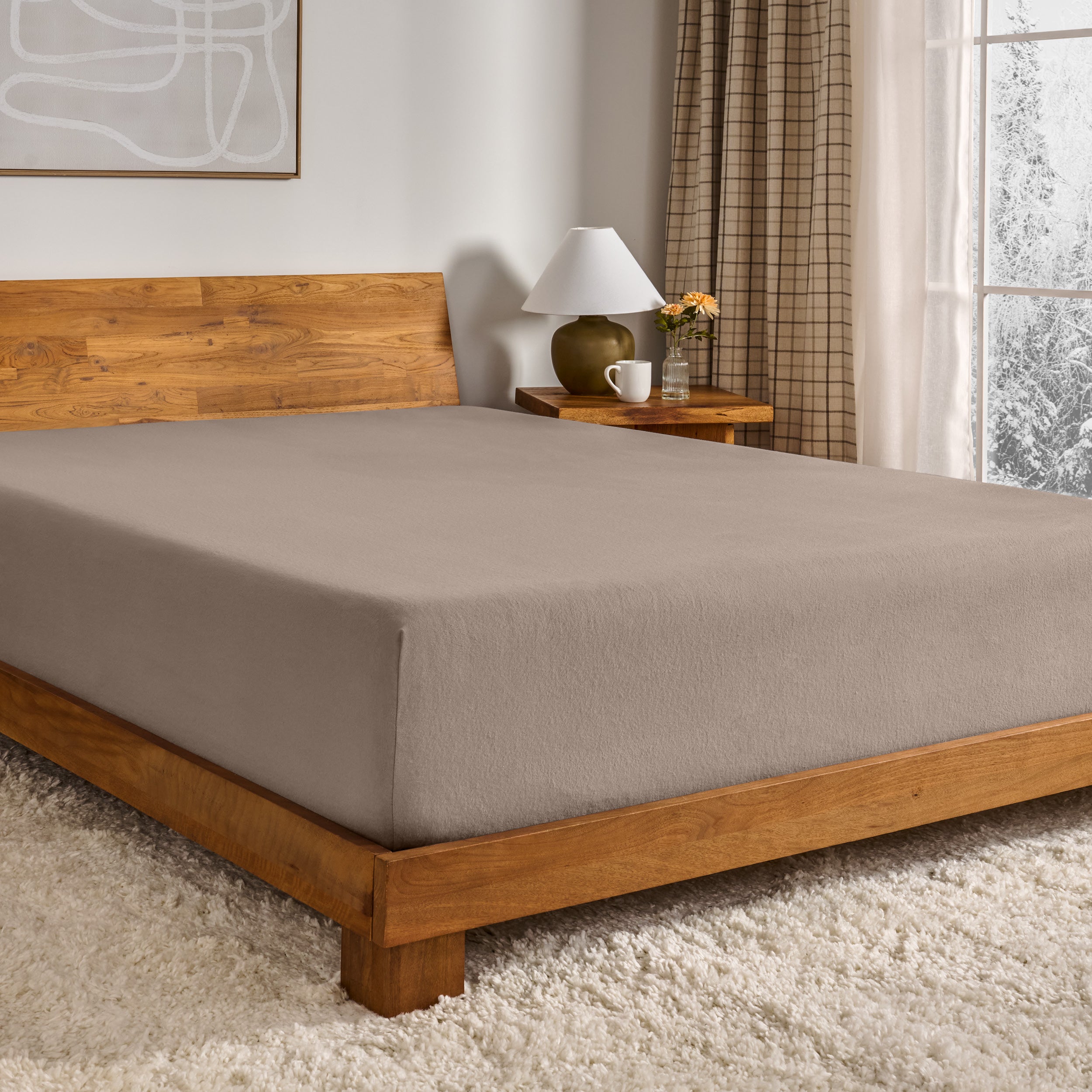 Taupe fitted sheet on a wooden bed in a bedroom setting