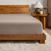 A flannel fitted sheet on a mattress with a wooden bed frame