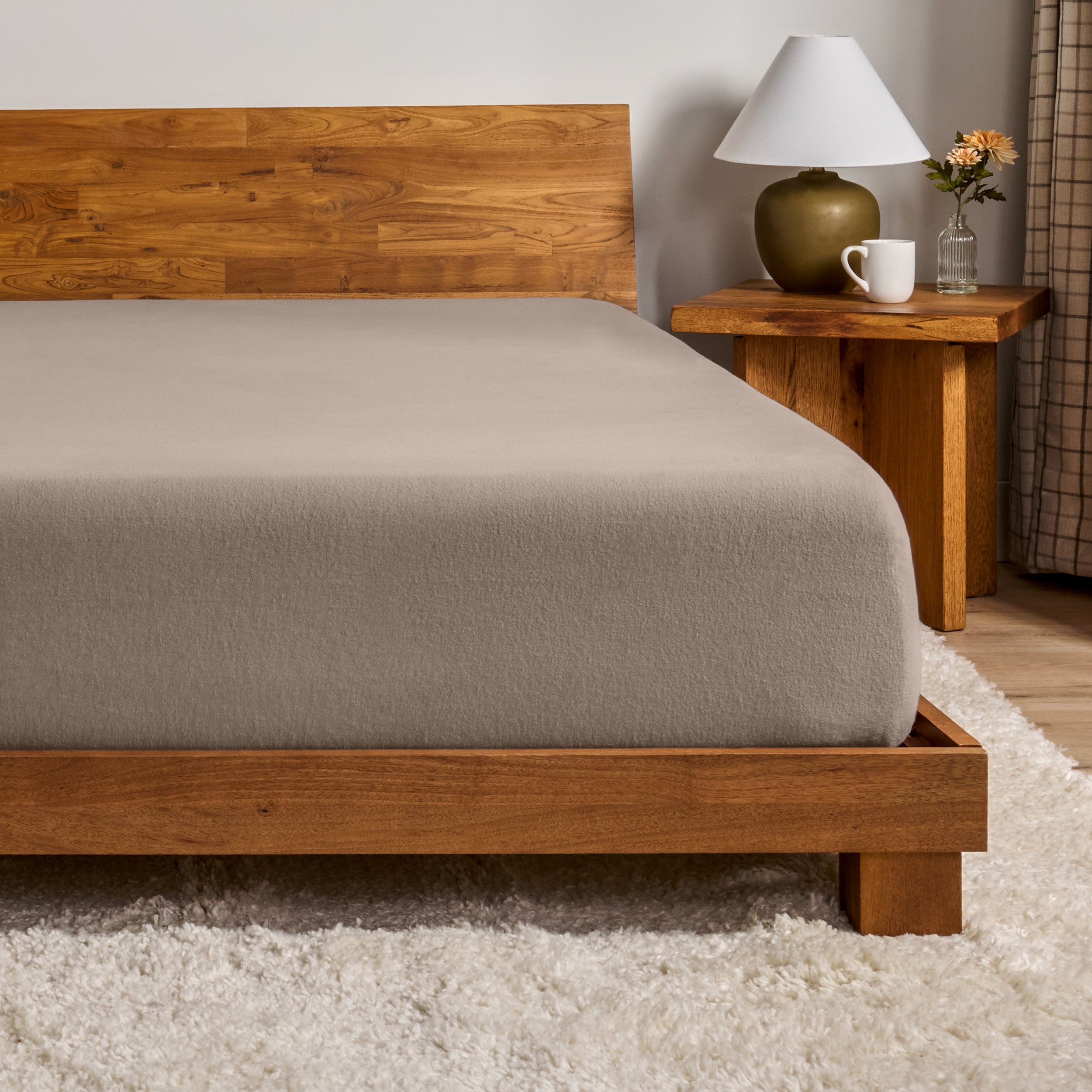 A flannel fitted sheet on a mattress with a wooden bed frame