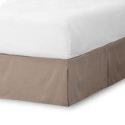 The corner of a bed skirt on a bed frame