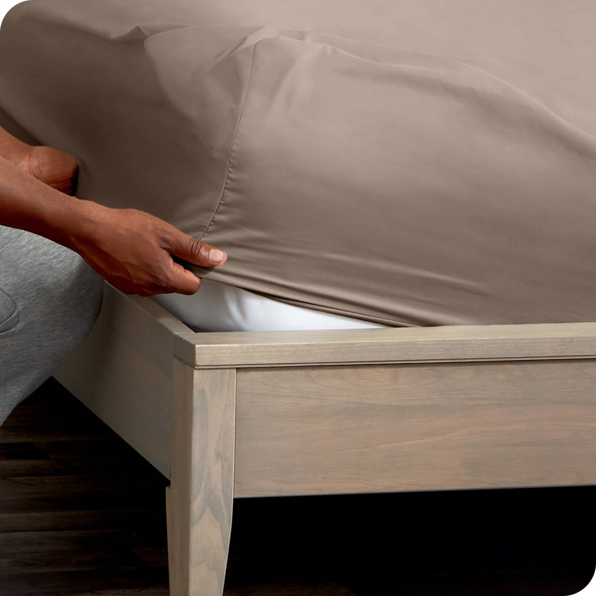 Person adjusting a fitted sheet on a mattress