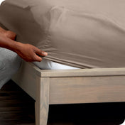 Person adjusting a fitted sheet on a mattress