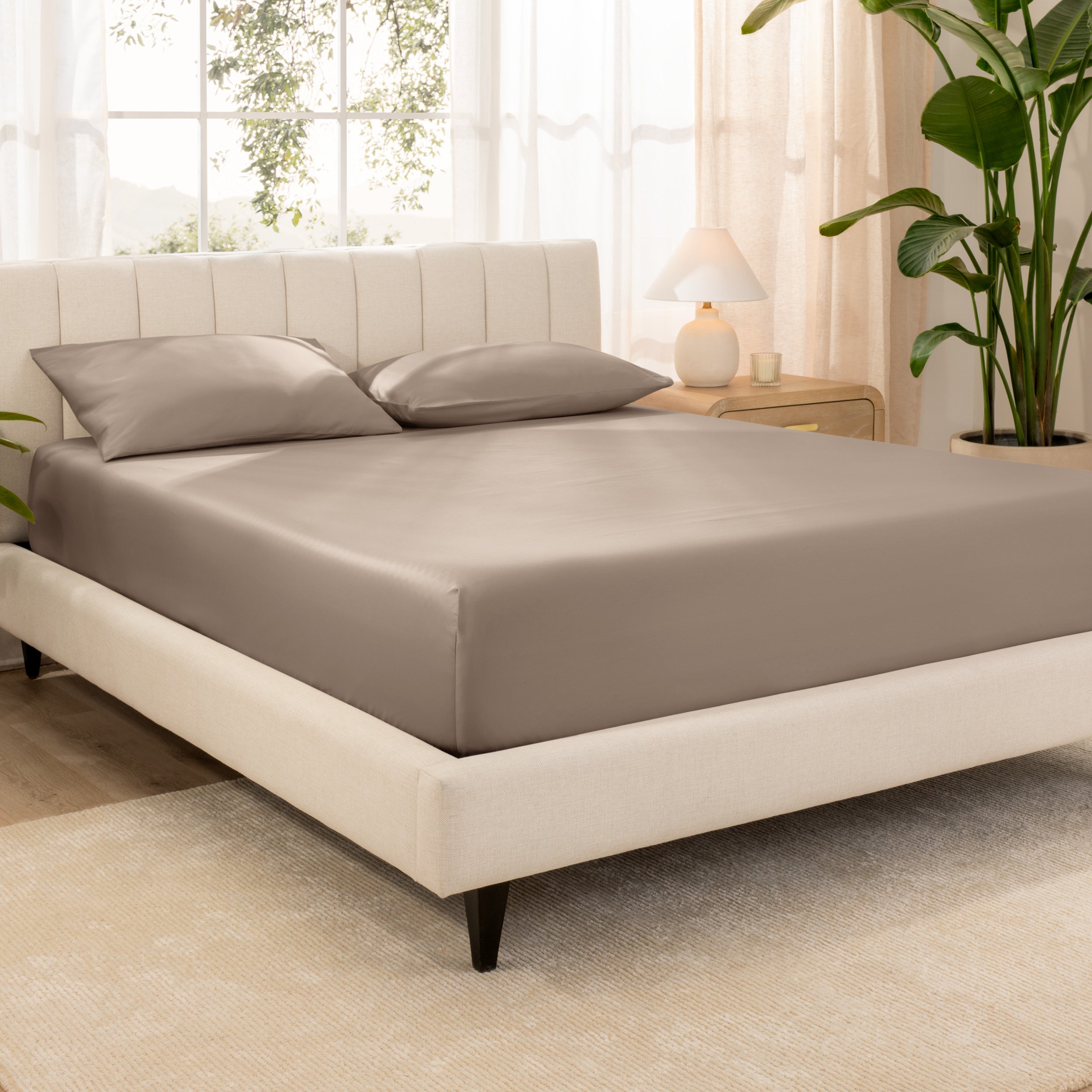 A bed made with an organic cotton sateen fitted sheet and matching pillowcases on pillows