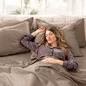 A woman is sleeping on a bed made with organic cotton sateen sheets