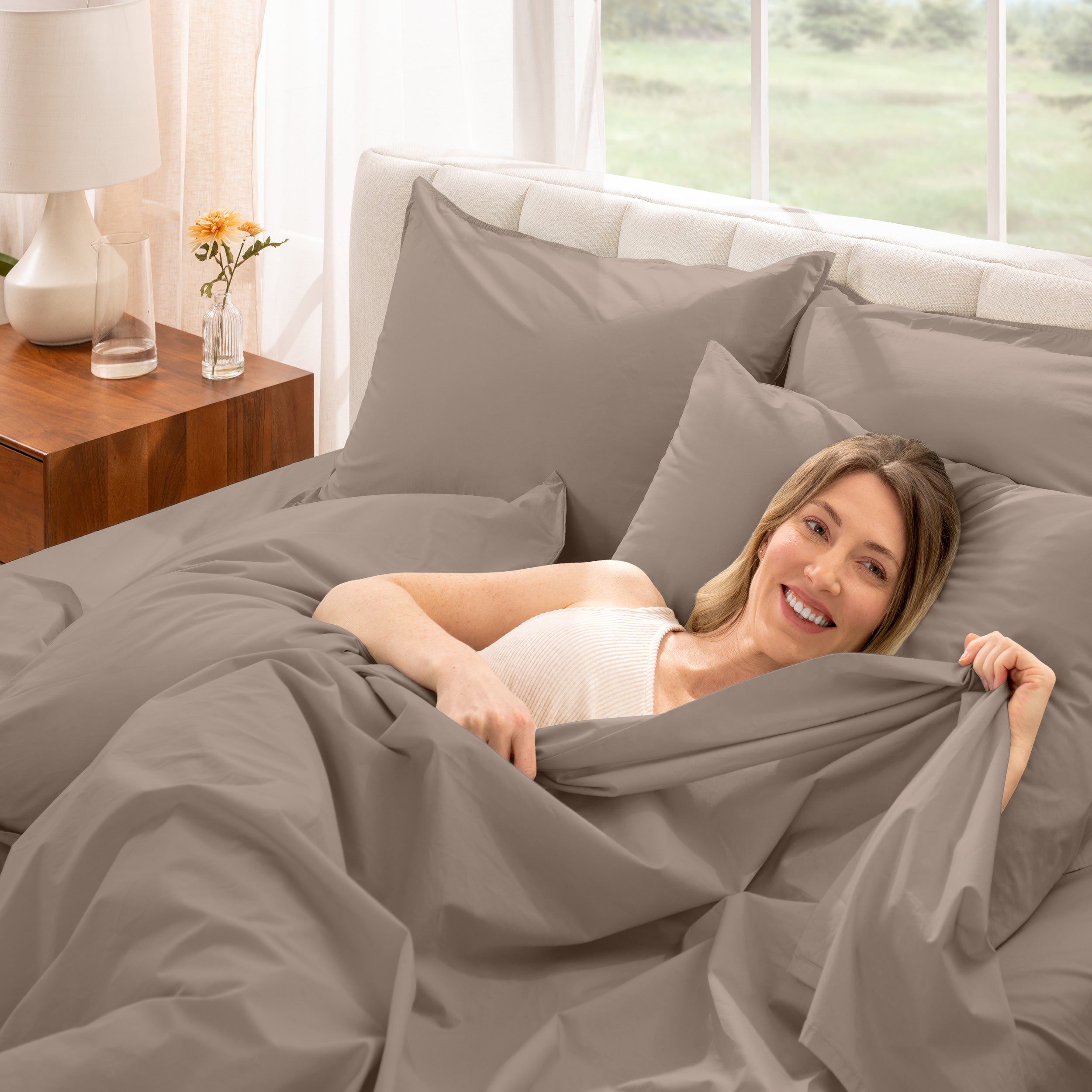 A woman is lying on a bed make with percale sheets and pillowcases