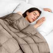 Woman sleeping peacefully under a weighted blanket with white pillows
