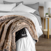 Blanket with 'Bare' branding on a bed in a bedroom setting