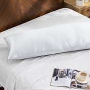 Bamboo pillow on a bed with a magazine and cup of coffee on a wooden nightstand.