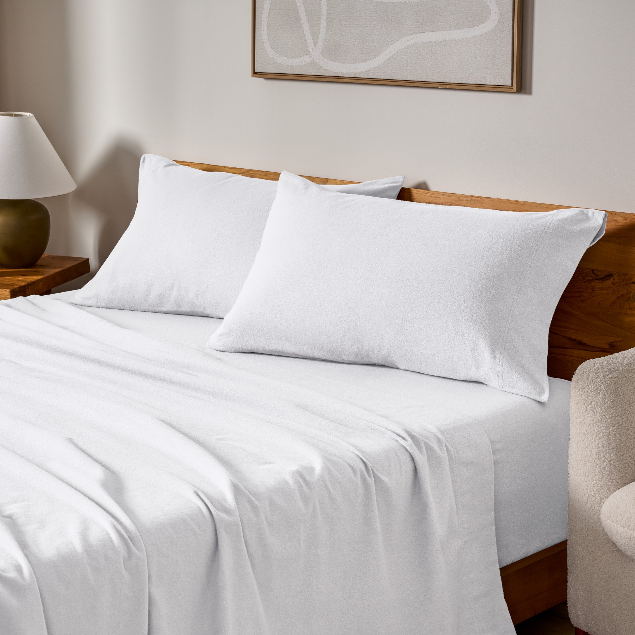 Cotton flannel sheets and pillows on a wooden bed in a bedroom setting.
