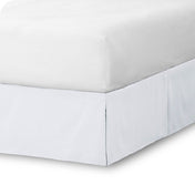 The corner of a bed skirt on a bed frame