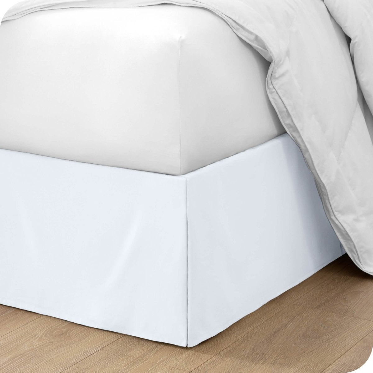 The corner of a bed with a bed skirt and comforter on it